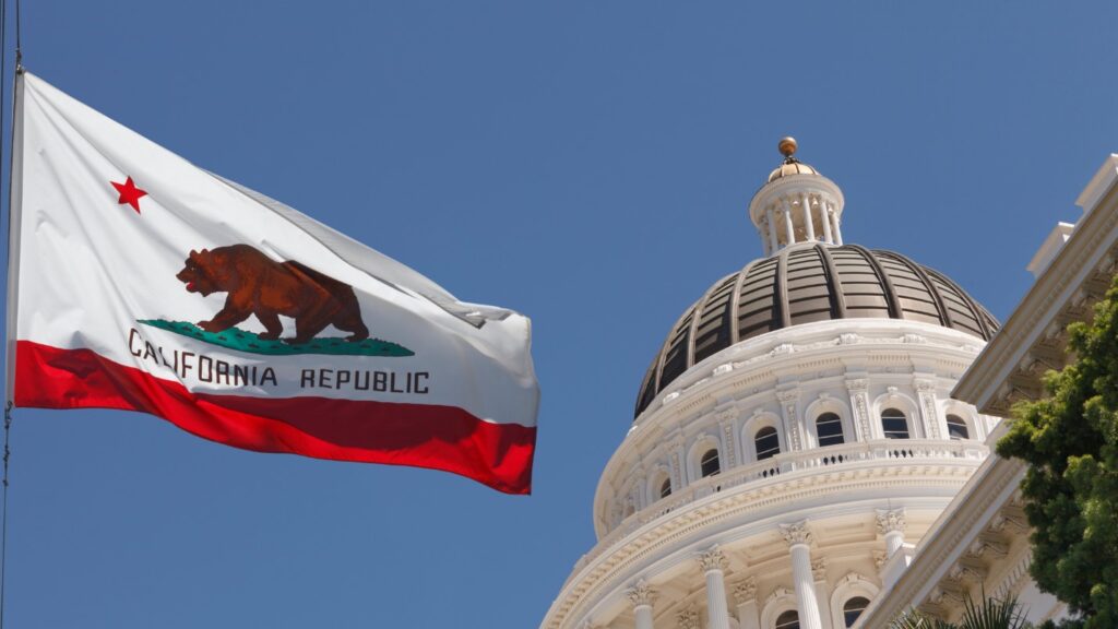 A California State Flag Flies Next to a California Government Building.