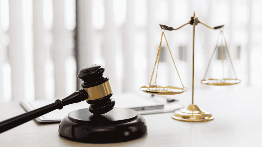 A set of golden scales sits on a desk next to a judges gavel.