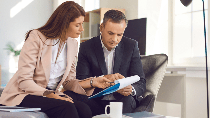 Two people in business outfits go over legal paperwork together.