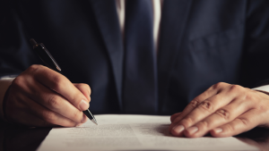A lawyer examines a lengthy legal document while holding a pen.