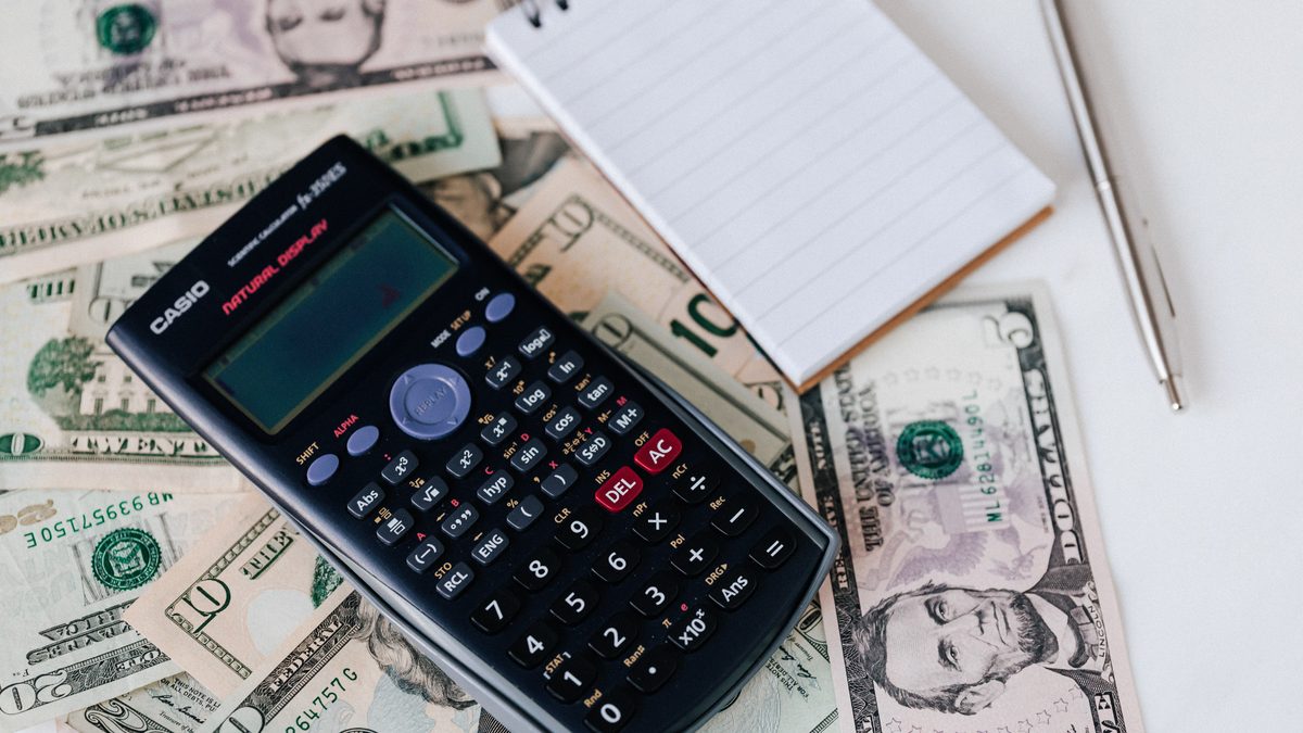 Calculator and notepad on cash used to estimate lost note bond cost in California Calculator, cash and a notepad used to estimate the cost of a lost note bond in California
